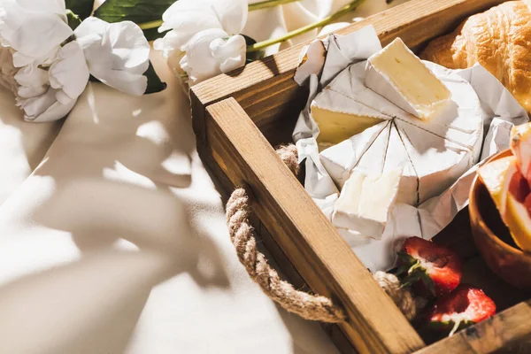 クロワッサン キャンベルト イチゴの木のトレイの上のフランスの朝食のビューを閉じます牡丹と質感の白い布 — ストック写真