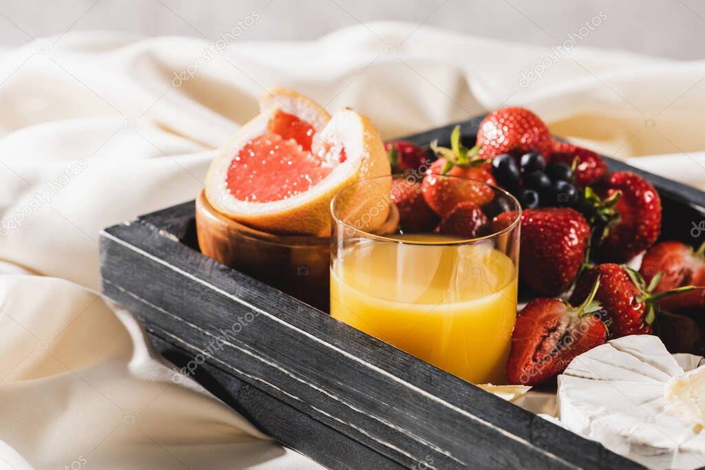 close up view of french breakfast with grapefruit, Camembert, orange juice, berries on wooden tray