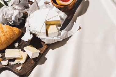 Fransız kahvaltısının kruvasan, Camembert, şakayık beyaz masa örtüsü üzerinde tahta kesme tahtası.