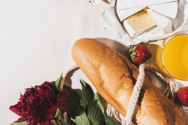 Fransız kahvaltısının baget, Camembert, portakal suyu, çilek ve şakayıklı beyaz masa örtüsü manzarası.