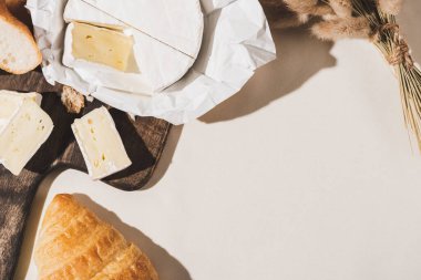 Fransız kahvaltısının kruvasanla üst görüntüsü, Camembert ahşap kesme tahtası beyaz masa örtüsü.