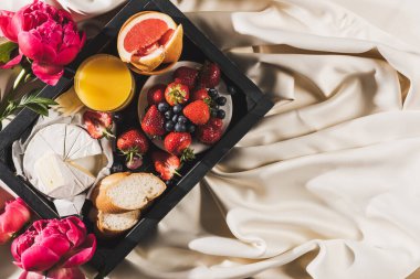 Greyfurtlu Fransız kahvaltısı, Camembert peyniri, portakal suyu, böğürtlen ve ekmeği beyaz masa örtüsünün yanındaki tepside.
