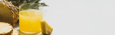 Taze ananas suyu, beyaz arka planda leziz meyvelerin yanında panoramik yönelimli.