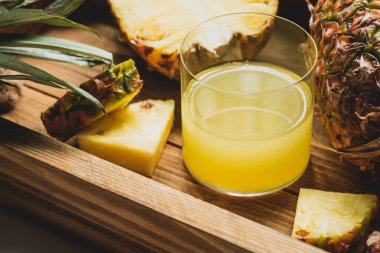 Taze ananas suyu manzarasını kapat ve ahşap tepside lezzetli meyveler kes.