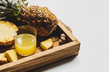 Taze ananas suyu ve beyaz arka planda ahşap tepside lezzetli meyveler.