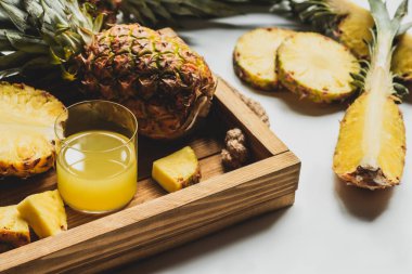 Taze ananas suyu ve beyaz arka planda ahşap tepside lezzetli meyveler.