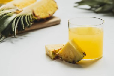 Taze ananas suyunun seçici odak noktası beyaz arka planda kesilmiş lezzetli meyveler.
