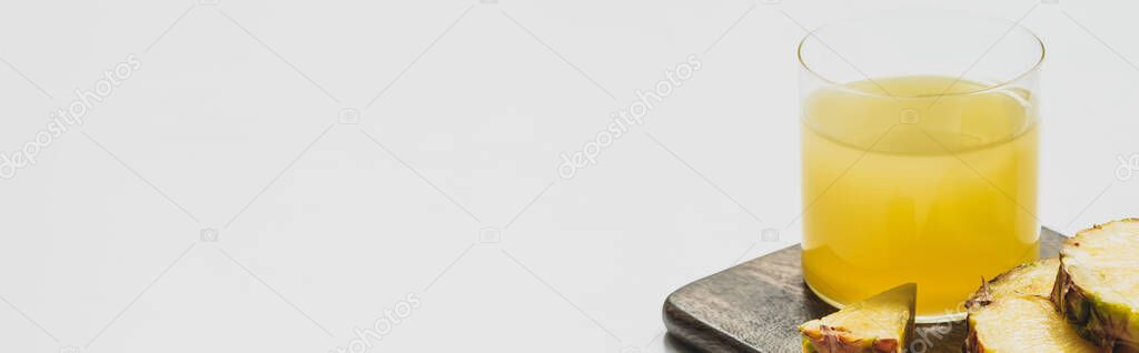 fresh pineapple juice in glass near cut delicious fruit on wooden cutting board on white background, panoramic orientation