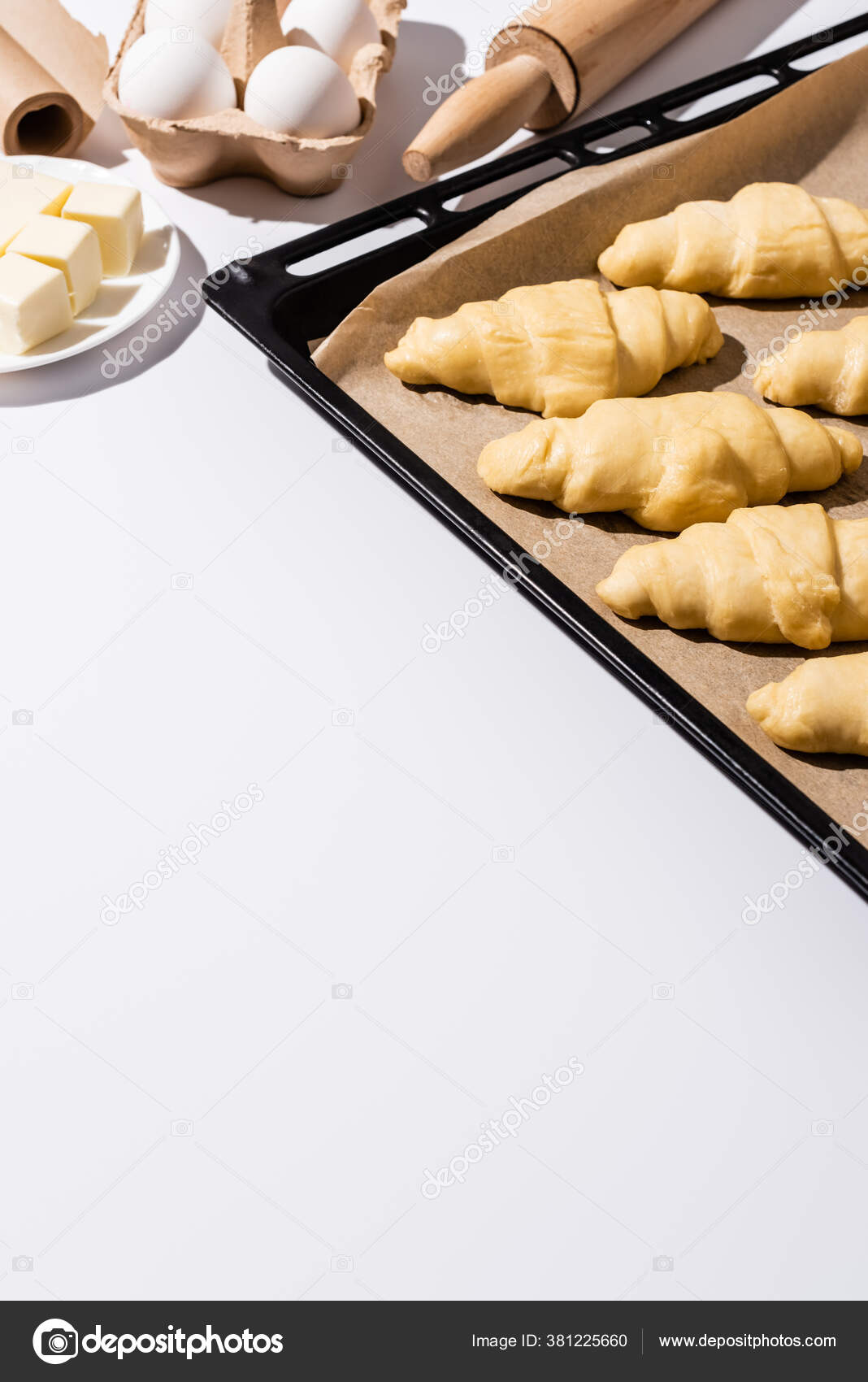selective-focus-raw-croissants-baking-tray-rolling-pin-parchment-paper