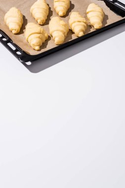 Pişirme tepsisindeki çiğ kruvasanlar beyaz arka planda