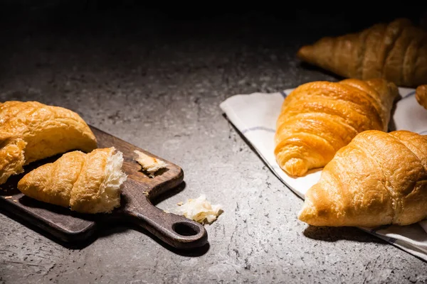Friss Sült Croissant Törülközőn Közel Vágódeszka Beton Szürke Felületen Sötétben — Stock Fotó