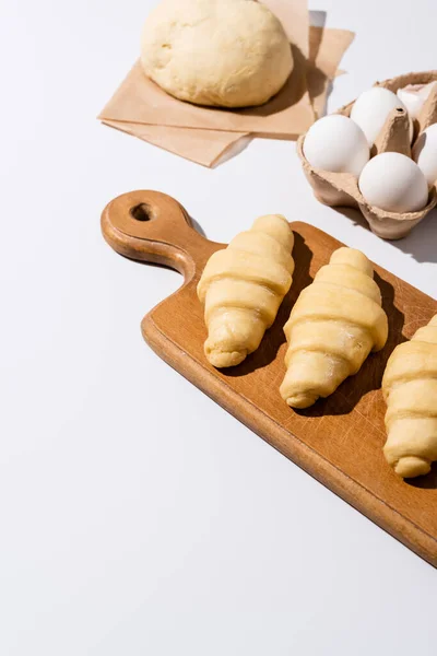 Rauwe Croissants Houten Snijplank Bij Eieren Deeg Witte Achtergrond — Stockfoto