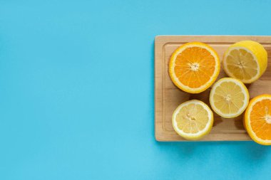 Olgunlaşmış limon ve portakalın üst görüntüsü mavi arka planda ahşap kesim tahtasında