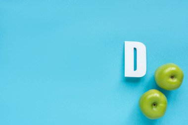 top view of ripe green apples and letter D on blue background clipart