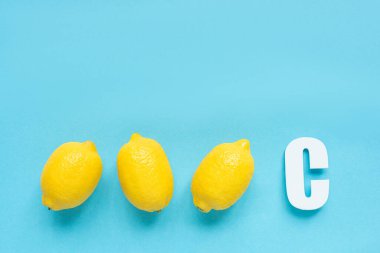 Olgun sarı limonların üst görüntüsü ve mavi arkaplanda C harfi.