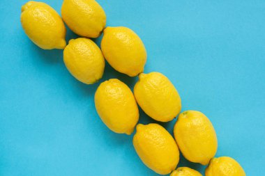 Düz, mavi zemin üzerinde olgun sarı limonlarla yatıyordu
