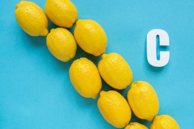 Olgun sarı limonları ve mavi arka planda C harfi ile düz yatıyordu.