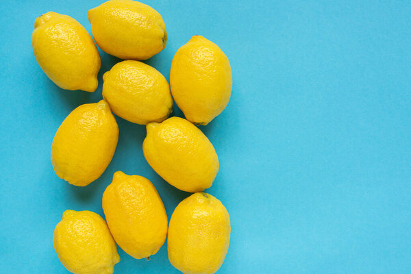 верхний вид спелых желтых лимонов на голубом фоне
