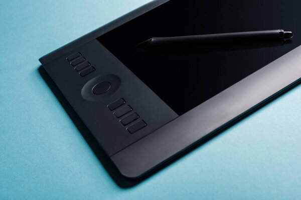 Close up view of graphics tablet and stylus on blue surface