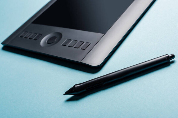 Close up view of stylus and graphics tablet on blue background