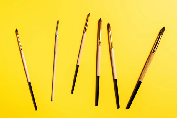 Top View Wooden Paintbrushes Yellow Surface — Stock Photo, Image