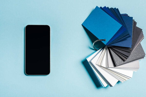 Top view of smartphone with blank screen and color swatches on blue background
