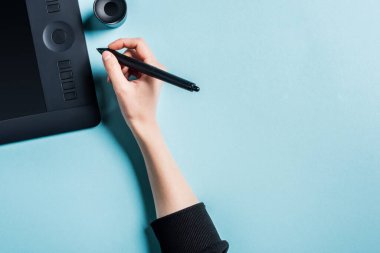 Tasarımcının stilini mavi arkaplanda grafik tabletinin yanında tutarken üst görünümü