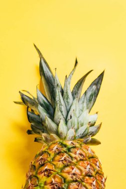 Sarı arka planda yeşil yapraklı taze ananas