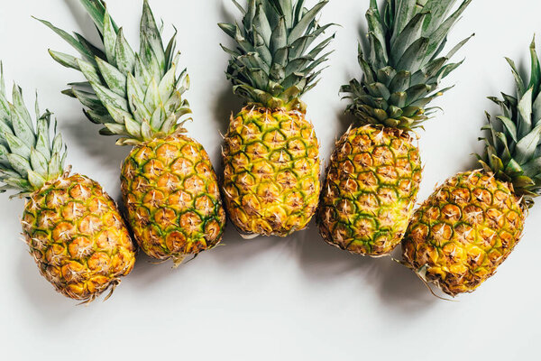 top view of fresh ripe pineapples with green leaves on white background