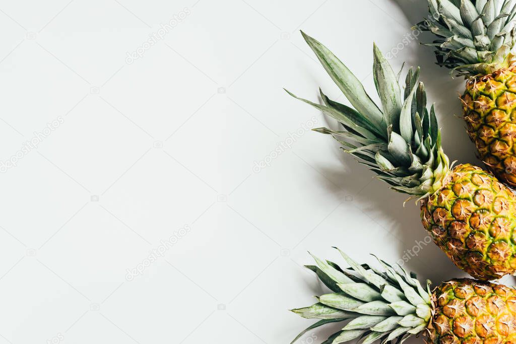 top view of ripe pineapples with green leaves on white background