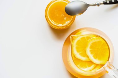 Beyaz arka planda kaşıkla balın yanında limonlu sıcak çay manzarası
