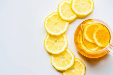 Beyaz arka planda limon dilimleri olan cam çaydanlıkta sıcak çay manzarası