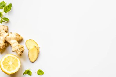Beyaz arkaplanda zencefil kökü, limon ve nane yapraklarının üst görünümü