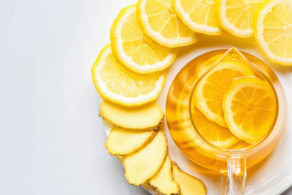 вид на горячий чай в стеклянном чайнике с ломтиками лимона на белом фоне
