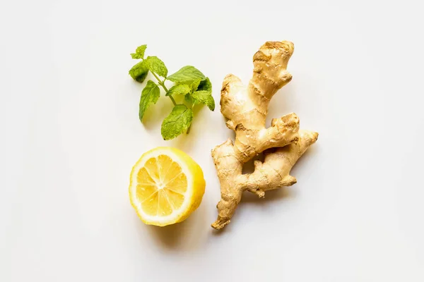 top view of ginger root, lemon and mint on white background