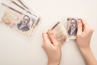 KYIV, UKRAINE - 25 Mart 2020: Japon yenini yırtan kadının beyaz banknota izole edilmiş görüntüsü