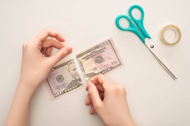 KYIV, UKRAINE - 25 Mart 2020: bir kadının dolar banknotunu tamir ederken beyaz bantla izole edilmiş koli bandıyla görüntüsü