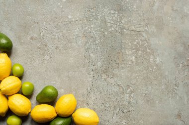Gri beton yüzeyde renkli limonlar, avokado ve limonların üst görünümü