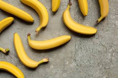 top view of colorful delicious bananas on grey concrete surface clipart