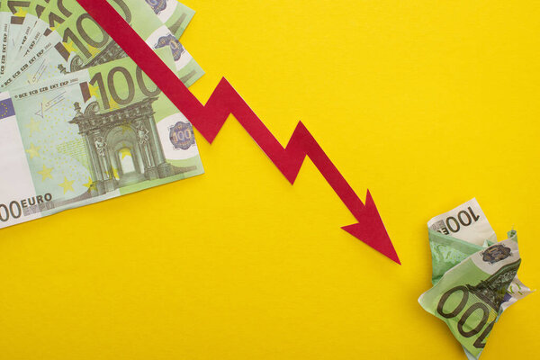 KYIV, UKRAINE - MARCH 25, 2020: top view of crisis graph and euro banknotes isolated on yellow 
