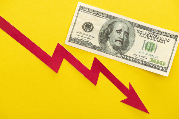 KYIV, UKRAINE - MARCH 25, 2020: top view of dollar banknote with sad face drawing near crisis graph isolated on yellow 