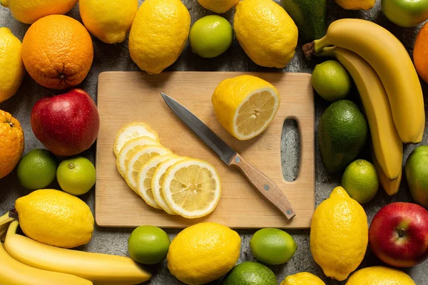 顶部的美味五彩缤纷的水果和木制切菜板与柠檬片和刀 — 图库照片