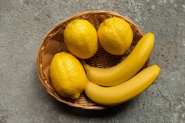 Top View Colorful Bananas Lemons Wicker Basket Grey Concrete Surface — Stock Photo, Image