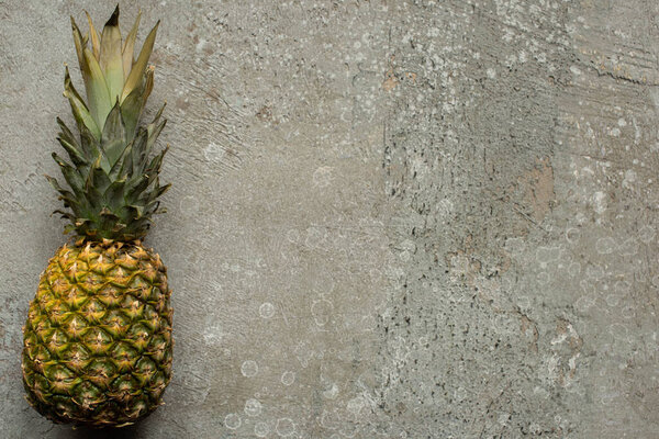 top view of ripe pineapple on grey concrete surface with copy space