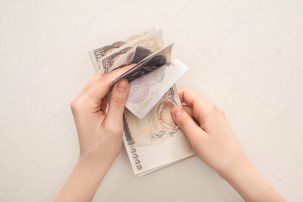 cropped view of woman counting japanese yen banknotes isolated on white