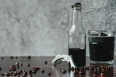 Soğuk kahve bardakta ve şişede. Açacak ve kahve çekirdekleri yanında.