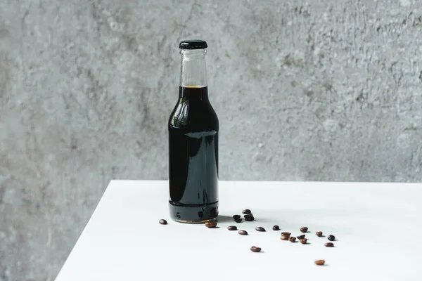 Холодный Кофе Бутылке Возле Кофейных Зерен Белом Столе — стоковое фото