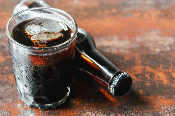 cold brew coffee with ice in glass and bottle on rusty surface