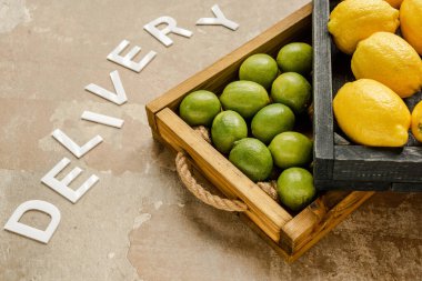 Olgun limonlar ve limonlar ahşap kutularda, yıpranmış yüzeyde kelime dağarcığının yanında.