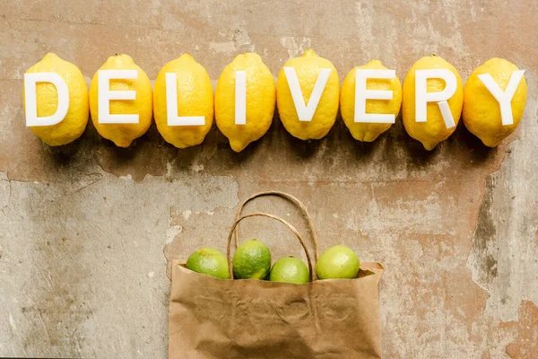 top view of word delivery on lemons near paper bag with limes on weathered surface